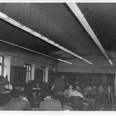 Interior view of library in Barbelin building with students studying at desks and talking.