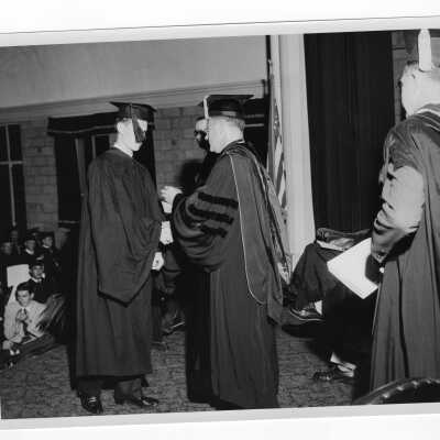Tropaia exercises during 1955 graduation/commencement with Edward G. Jacklin, S.J. and student.