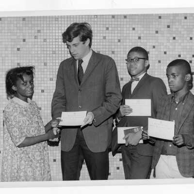 Children from Rhoads Public School receiving certificates/awards from student Tim Plunkett as part of student community service/outreach tutoring project.