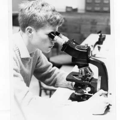 Student looking through microscope in science laboratory.