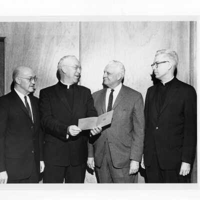 J. Joseph Bluett, S.J., showing Shaffrey award program to Mark Bauer, S.J., and others, 1961.