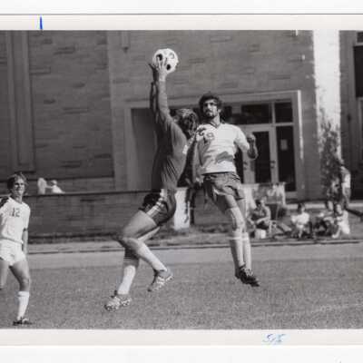 Men's soccer match on Finnesey Field with Post Hall (formerly Villiger) in background.