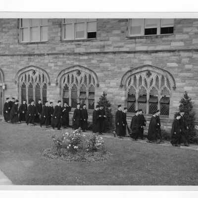Students dressed in cap and gown prcessing outside Saint Barbara's Church for Baccalaureate service as part of 1947 graduation/commencement ceremony.