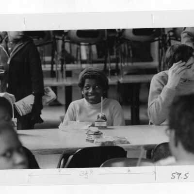 Students eating lunch with children in cafeteria as part of community service/outreach project.