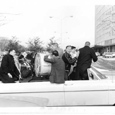 Student booster club pep rally/car parade down City Avenue. Students playing drum in convertible.