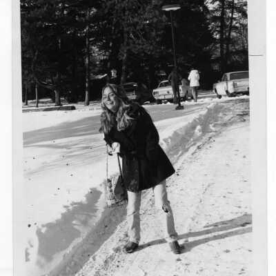 Women walking along shoveled path from parking lot with snow on ground.