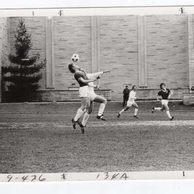 Men's soccer match on Finnesey Field with Post Hall (formerly Villiger) in background.
