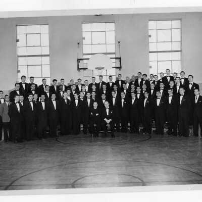 Students in Glee Club wearing black tuxedos pictured on basketball court of Reading Central Catholic High School possibly prior to performance.