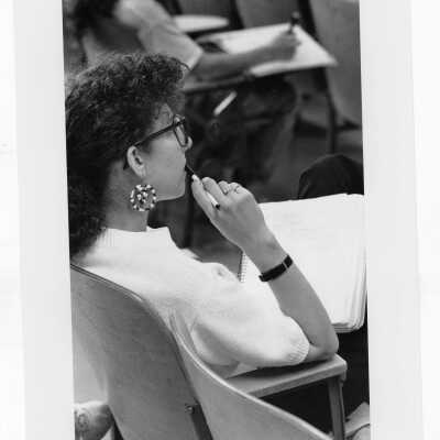 Woman student sitting at desk, listening to lecture.