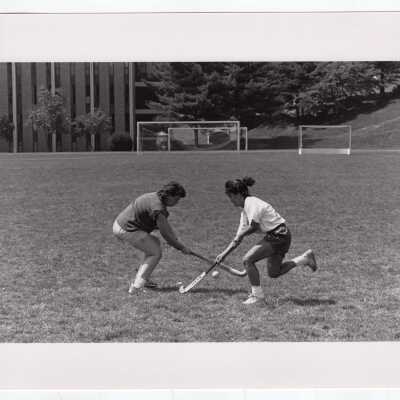 Two women practicing field hockey on Finnesey Field.