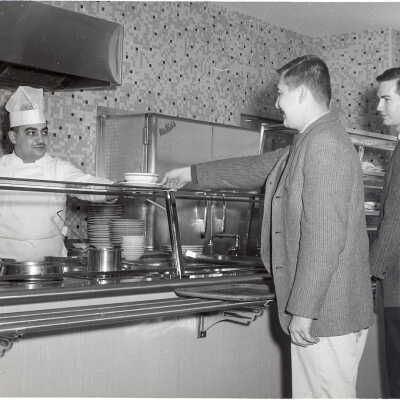 View of Campion cafeteria with two students in line and employee serving food.