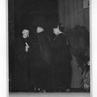 Edward G. Jacklin, S.J., conferring honorary degree on Thomas K. Finletter, Secretary of the Air Force, during academic convocation, October 28, 1951, as part of centennial celebration.