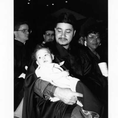 Graduate holding baby daughter during 1990 graduation/commencement.
