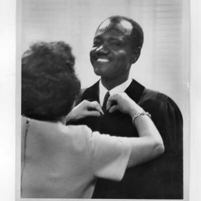 Madeline Conti helping the President of Chad, Francois Tombalbaye, with his academic gown, during convocation, October 26, 1970.