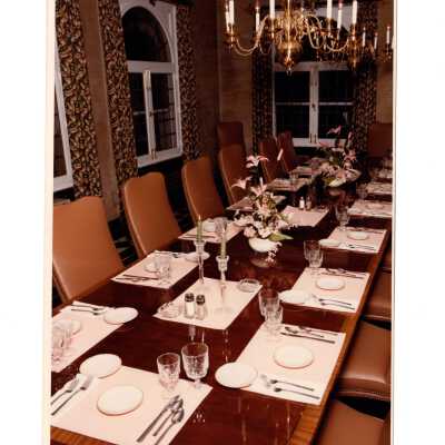 Banquet dining table set for meal in sun porch of Regis Hall.