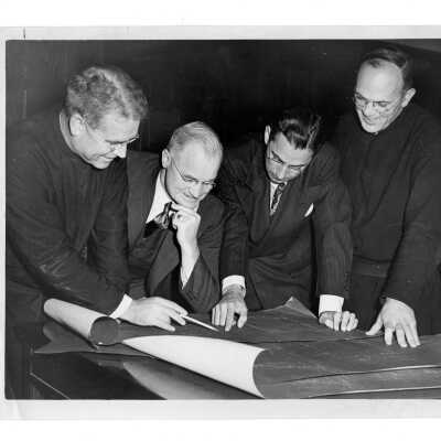 John Long, S.J. and others looking at blueprints for building.