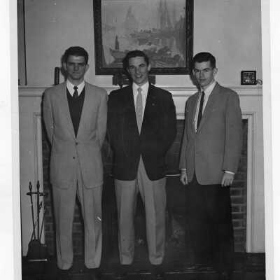 Three student residents of Barry Hall standing in front of fireplace.
