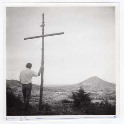 Student standing near cross on hill overlooking valley in Colombia during during Latin American Studies Institute Summer Service Project, summer 1970.