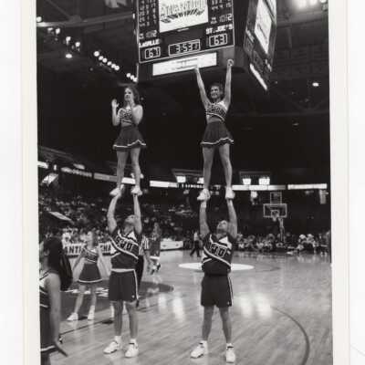 Men and women cheerleaders performing routine during basketball game.