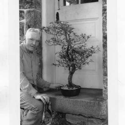 Robert Fitzgerald, S.J. (Brother) with his bonsai collection outside Loyola Hall.