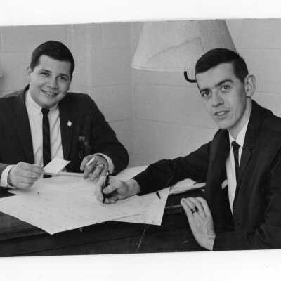 Student staff members of The Hawk newspaper, Knoblauh (editor) and Jay Friedman (senior editor) working at desk, one holding cigarette in hand.
