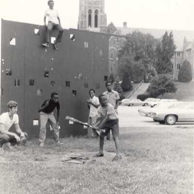 Student playing baseball with neighborhood children on SJU campus as part of community service/outreach program during summer.