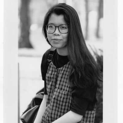 Woman student sitting outside on wall.