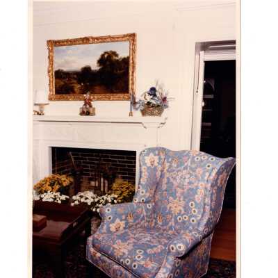 Interior view of room in Regis Hall with wing chair and fireplace.