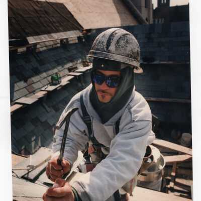 Workman laying roof on Mandeville Hall during construction.