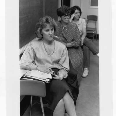 Three women students listening to lecture in classroom.