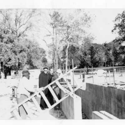 Donald I. MacLean, S.J. talking with workers at Sourin Residence Residence Center construction site.