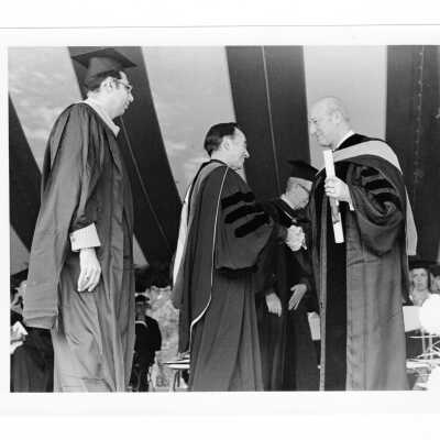 Terrence Toland, S.J. conferring honorary degree on James L. Hayes during 1976 graduation/commencement with Daniel DeLucca looking on.