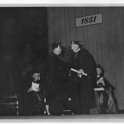 Edward G. Jacklin, S.J., conferring honorary degree on John Foster Dulles, U.S. Ambassador at Large, during academic convocation, October 28, 1951, as part of centennial celebration.