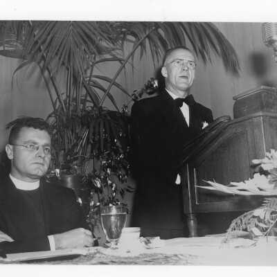 Edward G. Jacklin, S.J., listening to speaker (John Nason or Joseph P. Tully?) during banquet held in Field House as part of centennial anniversary celebration.