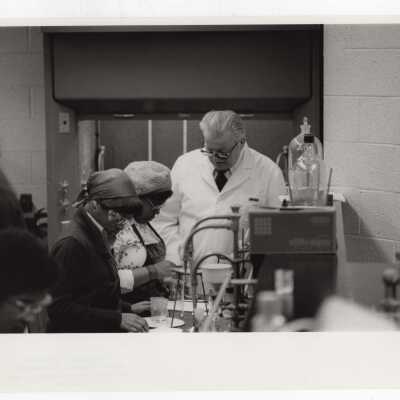 George Beichl, SJC chemistry professor, working with two high school students in laboratory as part of Chemistry Department's Science Motivation Program, c. 1972.