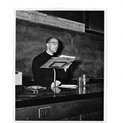 Interior view of physics amphitheater in Barbelin Lonergan building with Jesuit faculty member lecturing.