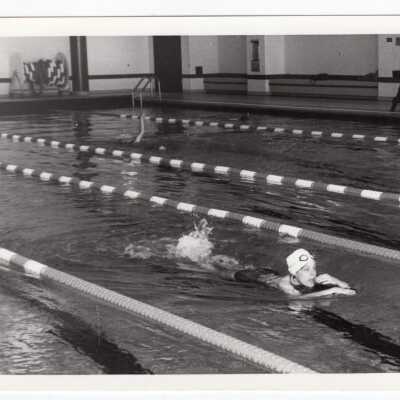 Student swimming in pool at sports recreation complex.