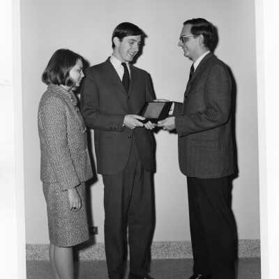 Student from Villiger Debating Society, Wayne Barrett, receiving award from Rosemont College Debate coach Thomas Miller while Sheila Williams, Rosemont College Debate Tournament chairman looks on.