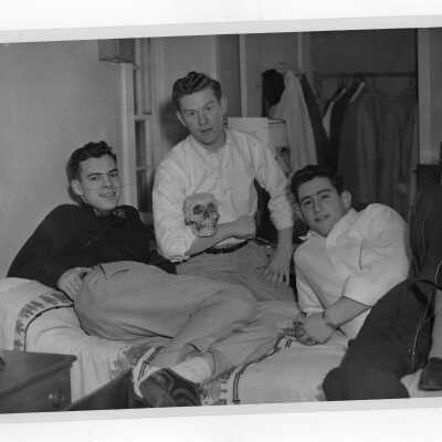 Three student residents of Barry Hall in dormitory room, one holding skull.
