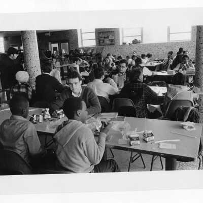 Students eating lunch with children in cafeteria as part of community service/outreach project.