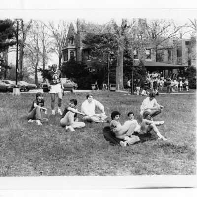 Students sitting on lawn and gathered on porch of Wolfington.