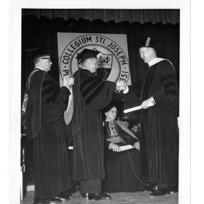 Dedication and convocation of Villiger (later Post) Academy of Food Marketing with William F. Maloney, S.J. conferring an honorary degree to Theodore R. Gamble. Also on stage are Michael P. Boland, S.J., and Archbishop John J. Krol.