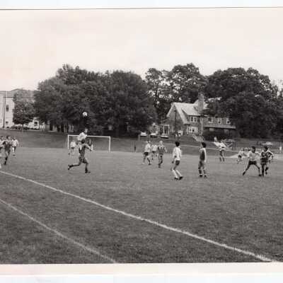 Men's soccer game on Finnesey Field with Field House in background.