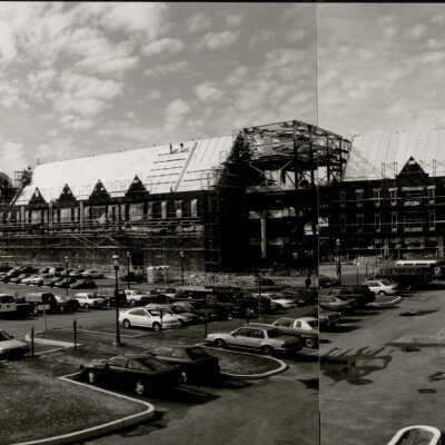 Exterior view of back of Mandeville Hall under construction as seen from parking lot near Field House with Barbelin Tower in background.