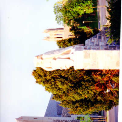 View of carved mascot hawk in front of Mandeville Hall with Barbelin Tower in distance.