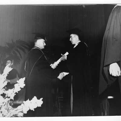 Graduate receiving degree from Edward G. Jacklin, S.J., during 1954 graduation/commencement.