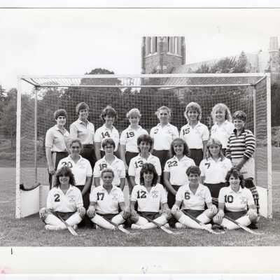 Group photo of women's field hockey team with Barbelin in background.