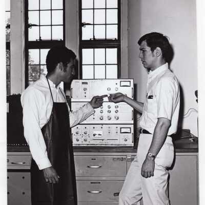 Two chemistry students in science laboratory working with gas chromatograph, c. 1970.