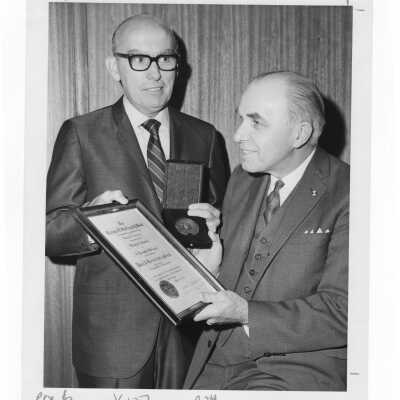 Shaffrey award recipient, Dr. Peter A. Herbut, showing medal and certificate to another individual, April 19, 1970.