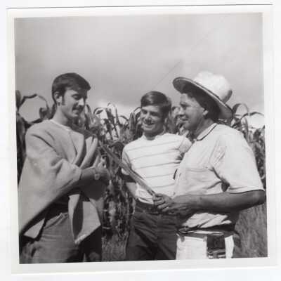 Two students standing with Colombian farmer holding machete knife near corn field during during Latin American Studies Institute Summer Service Project, summer 1970.
